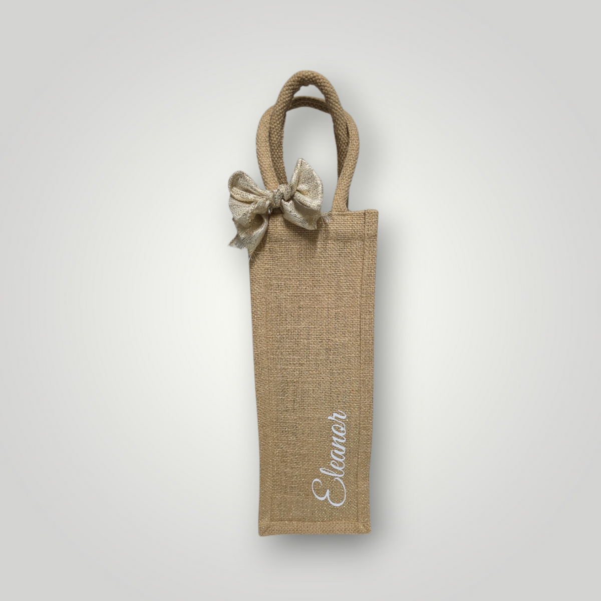 Personalised natural jute bottle bag with with bow, has gold shimmer thread and name in white script lettering